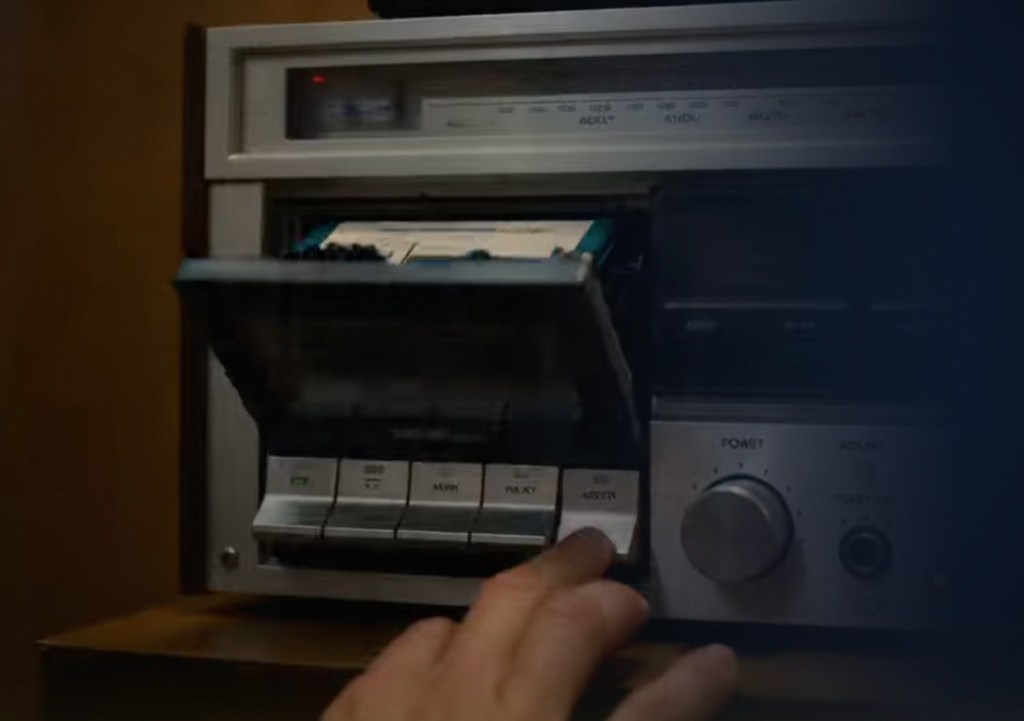 Hand pressing button on vintage cassette player.